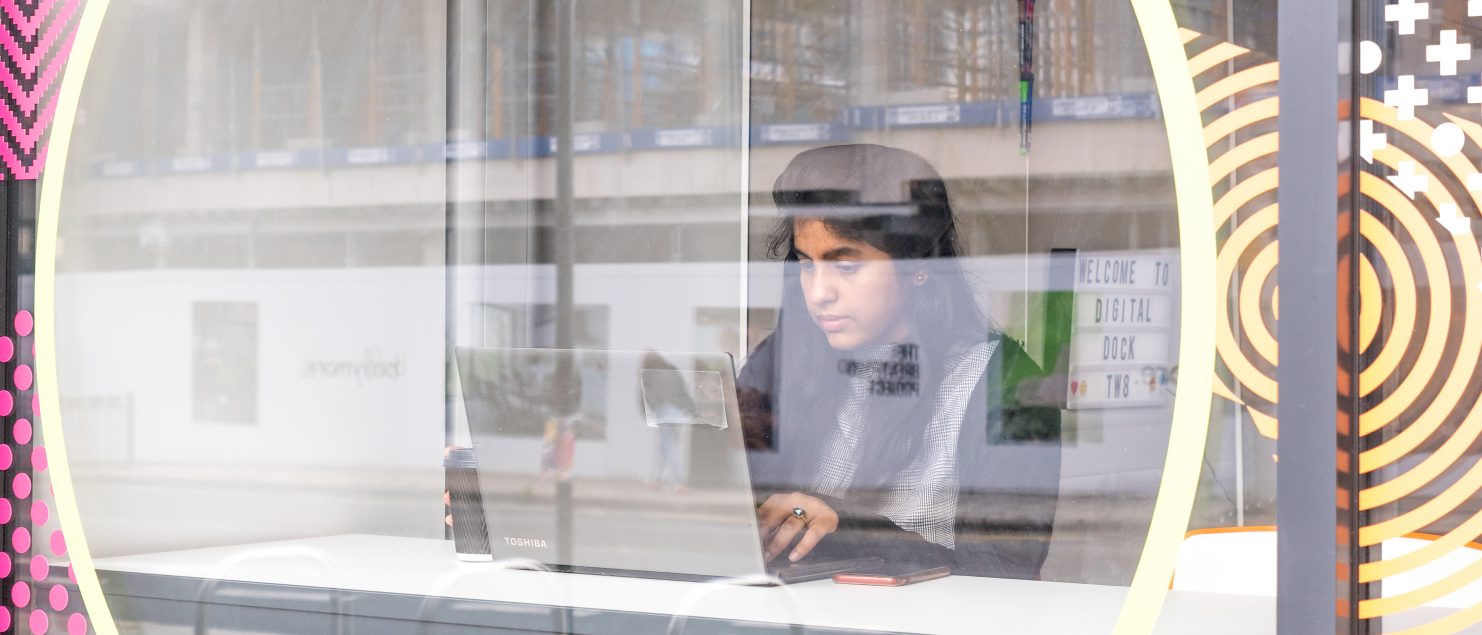 Creative personal branding photography showing a female professional working on a laptop inside the modern Digital Dock workspace in London by Sadia Barlow Photography